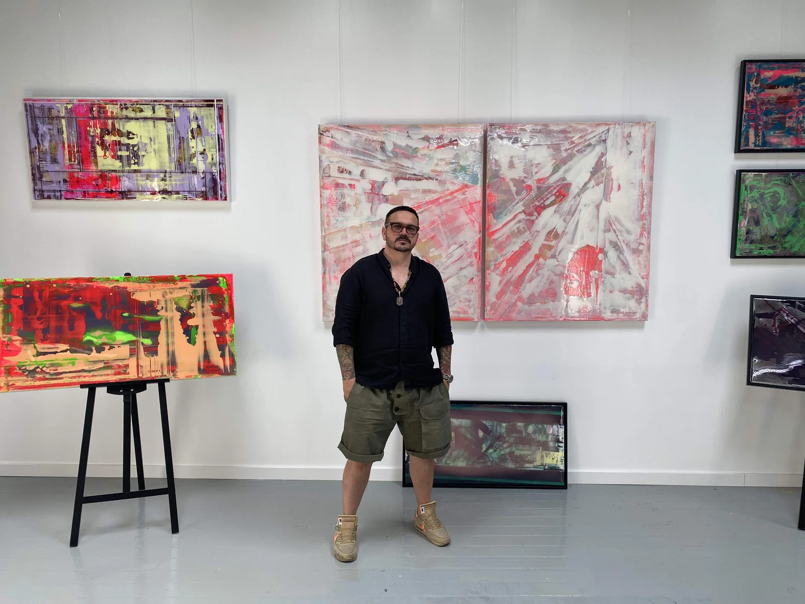 John Tonic vor mehreren seiner Arbeiten in einem Ausstellungsraum
